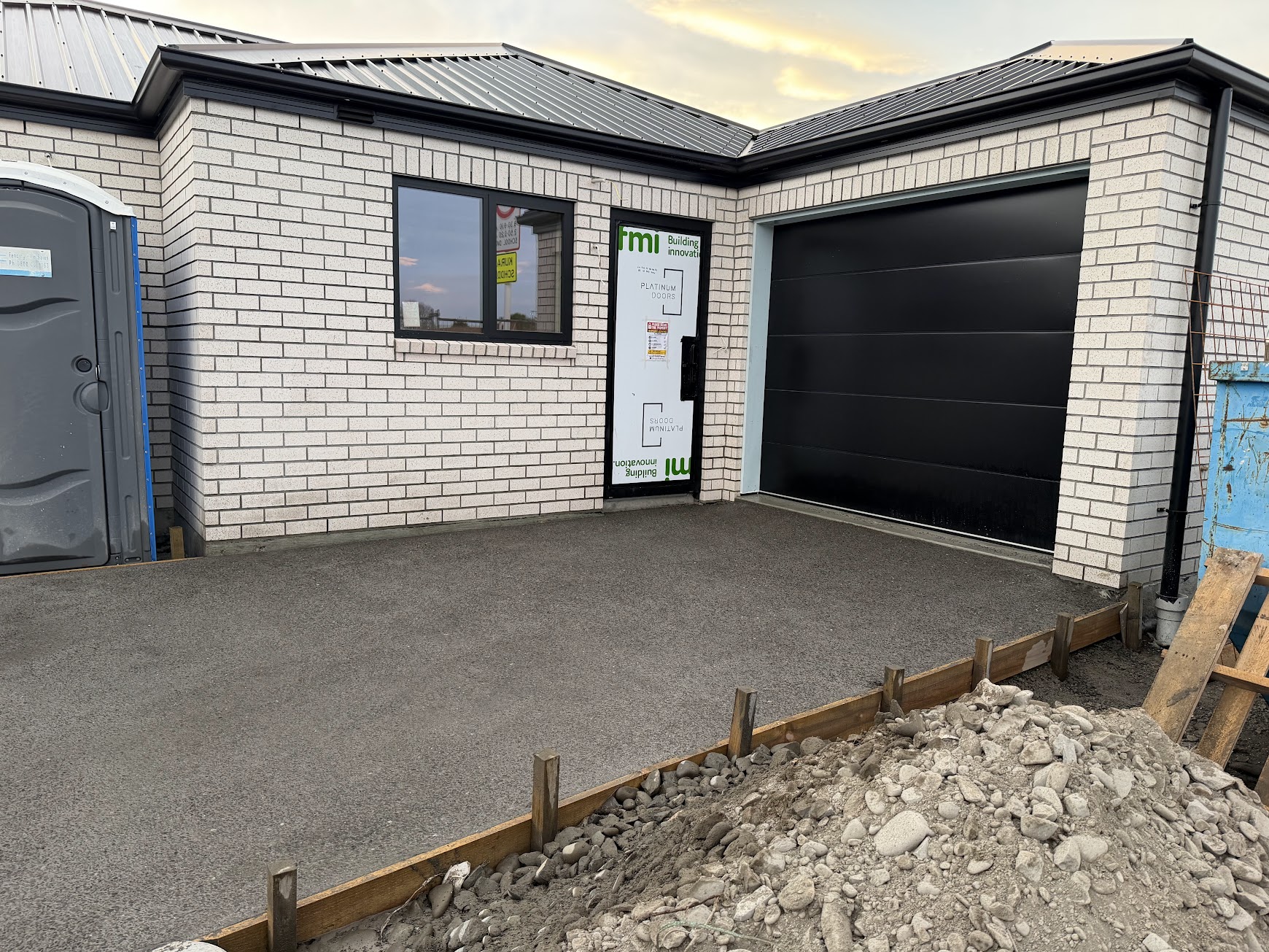 Pale brick walls, dark window frame and dark garage door during construction